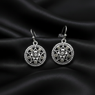 Silver floral earrings on black satin fabric