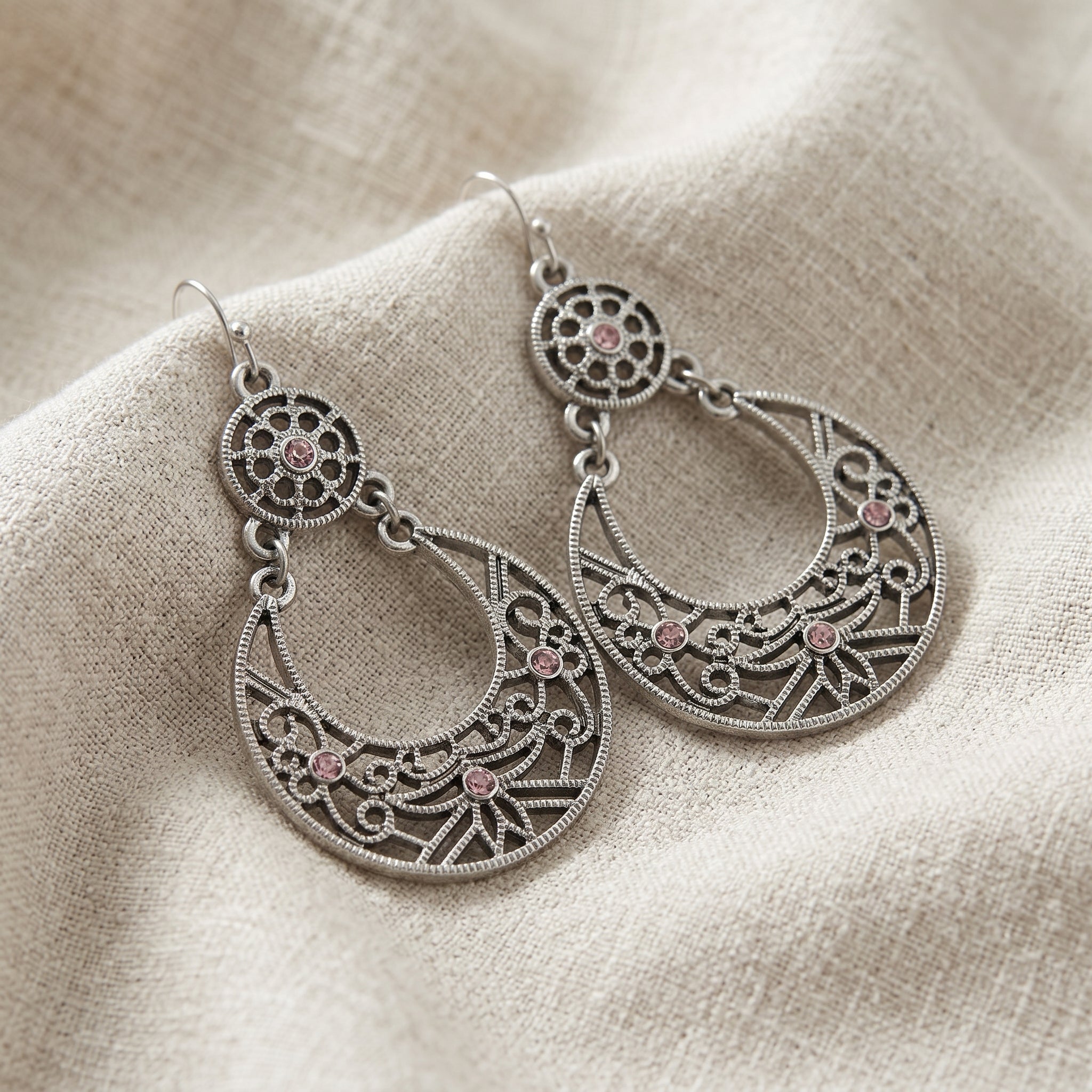 Pair of silver tone Amethyst Purple Large Filigree Drop Earrings with intricate designs on a beige fabric background