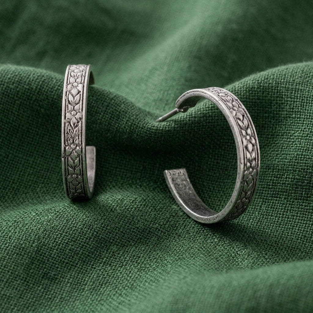 Tiny Etched Silver Tone Floral Hoop Earrings resting on forest green linen