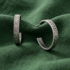 Tiny Etched Silver Tone Floral Hoop Earrings resting on forest green linen
