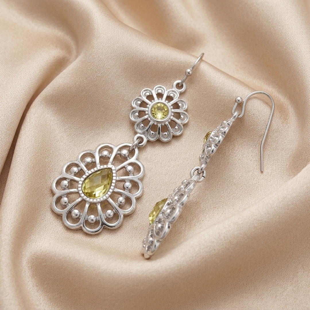 Silver earrings with yellow crystals on a beige fabric background