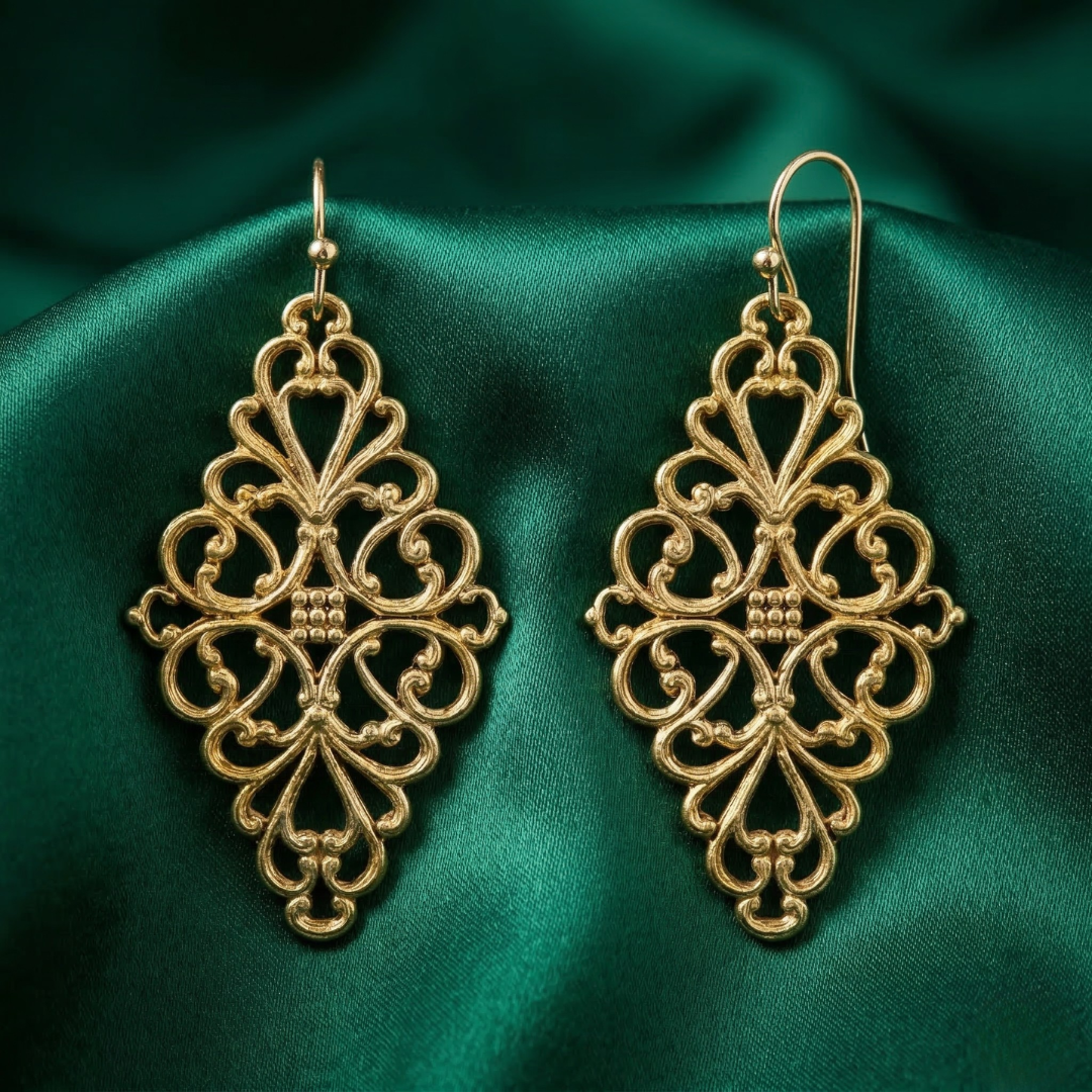 Gold filigree earrings on a green satin background