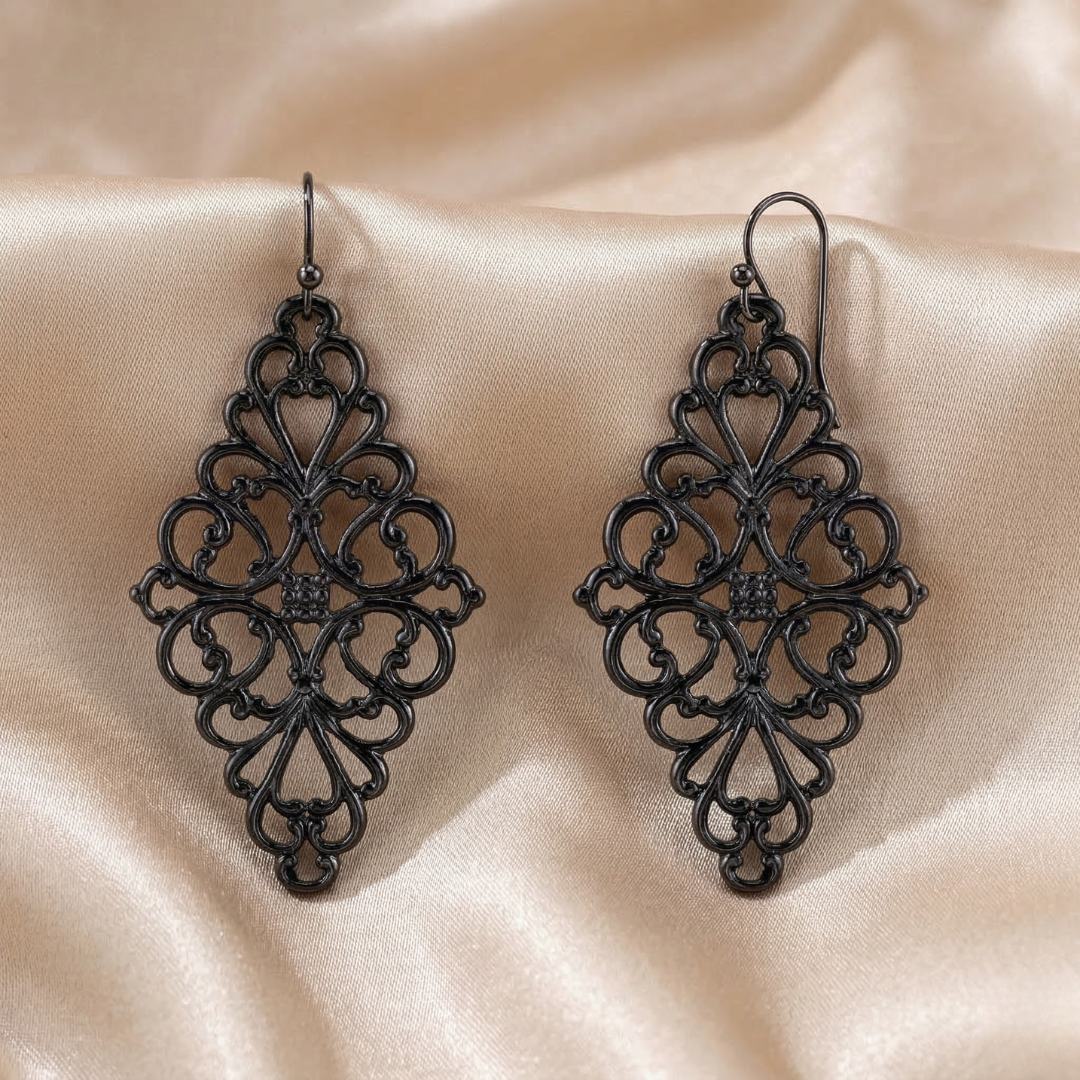 Pair of black filigree earrings on a beige fabric background