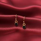 Gold earrings with black stones on a red satin background