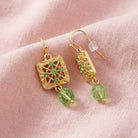 Square Green Crystal Filigree Drop Bead Earrings resting on light pink linen