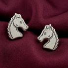 Silver horse head earrings on a burgundy fabric background