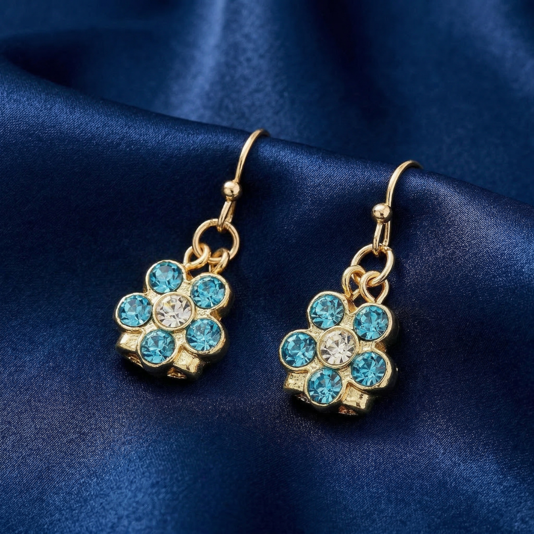 Gold earrings with blue and clear crystals on a blue satin background