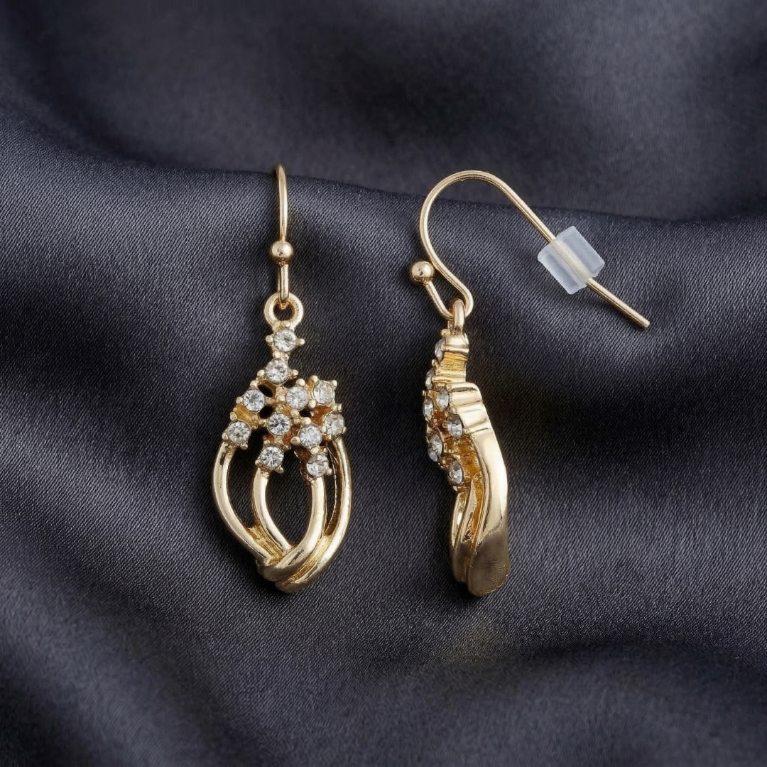 Gold earrings with crystal accents on a dark fabric background
