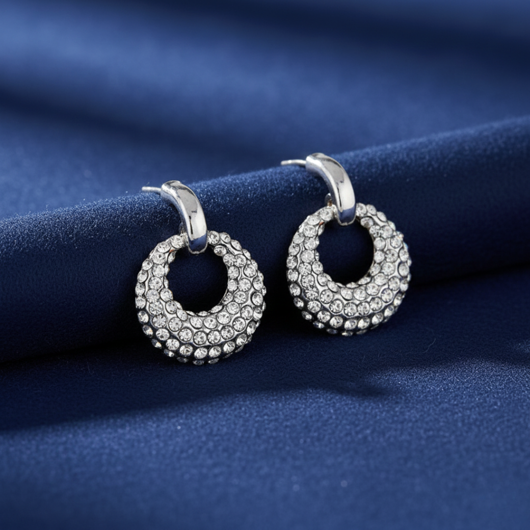 Silver hoop earrings with gemstones on a blue fabric background