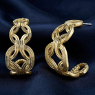 Gold tone hoop earrings on a dark blue fabric background