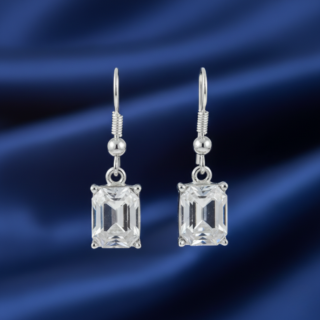 Silver earrings with glass crystals on a blue satin background