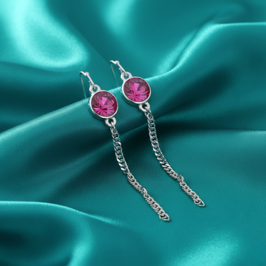 Silver earrings with pink crystals on a teal satin background