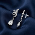 Silver earrings with teardrop-shaped crystals on a dark blue fabric background