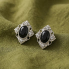 Black Stone Crystal Accent Clip On Earrings resting on olivine green linen