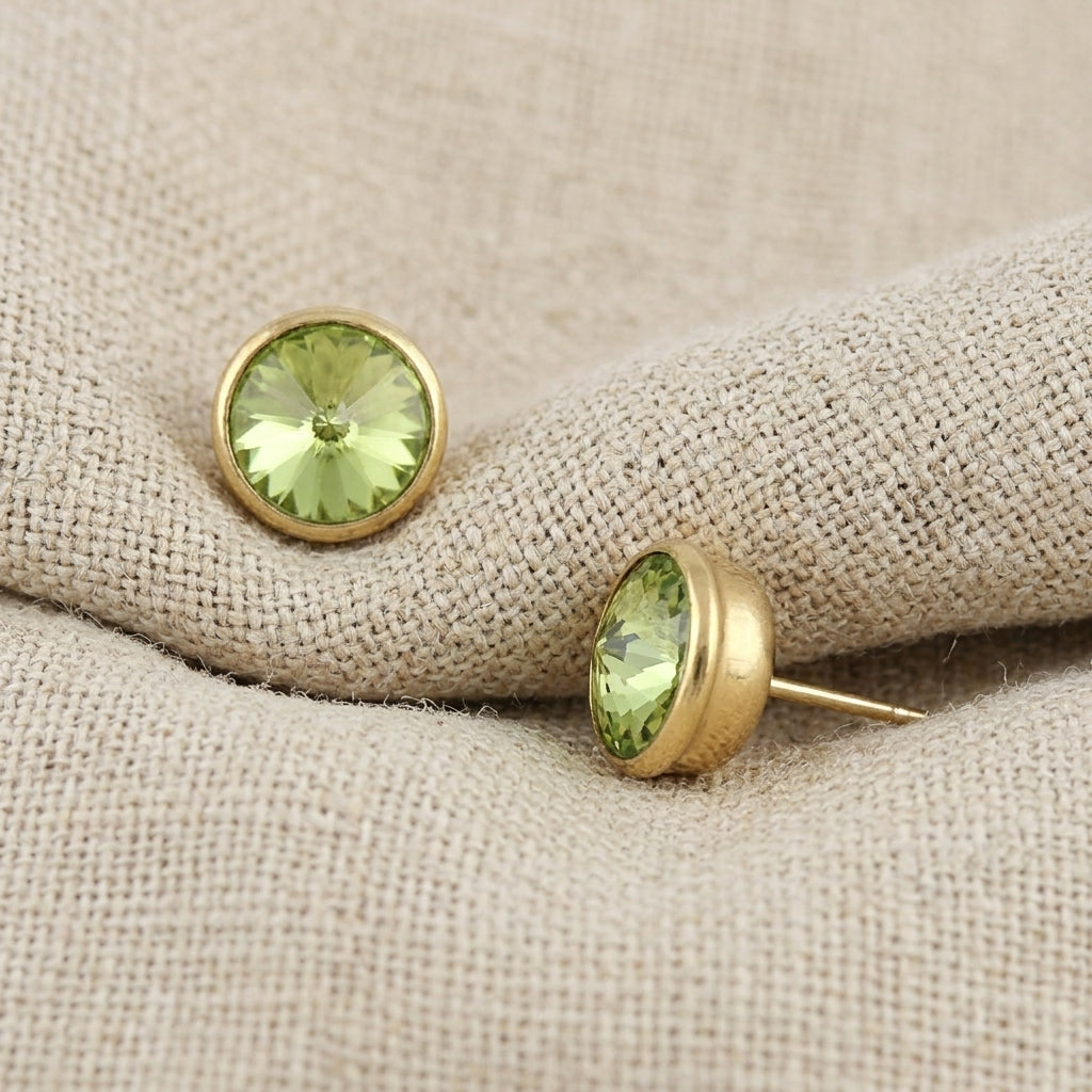 Round Sparkling Light Peridot Green Stud Earrings resting on beige linen