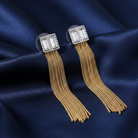 Gold tassel earrings with crystal tops on a blue satin background