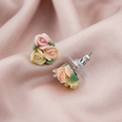 Multicolor floral porcelain rose earrings on a soft pink fabric background