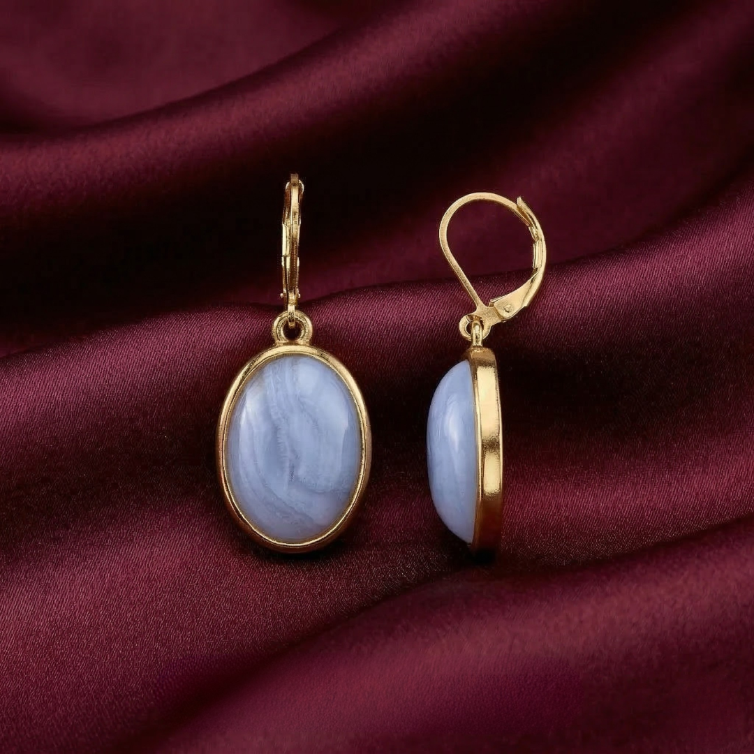 Gold earrings with blue stones on a burgundy fabric background