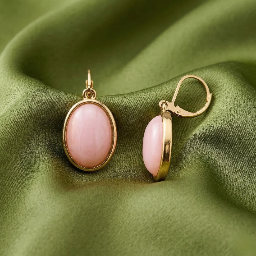 Pink earrings with gold accents on a green fabric background