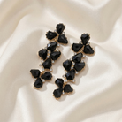 Black enamel gemstone earrings on a beige fabric background