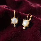 Antiquities Couture Faux Pearl and Crystal Leverback Drop Earrings displayed on a deep burgundy velvet fabric background.