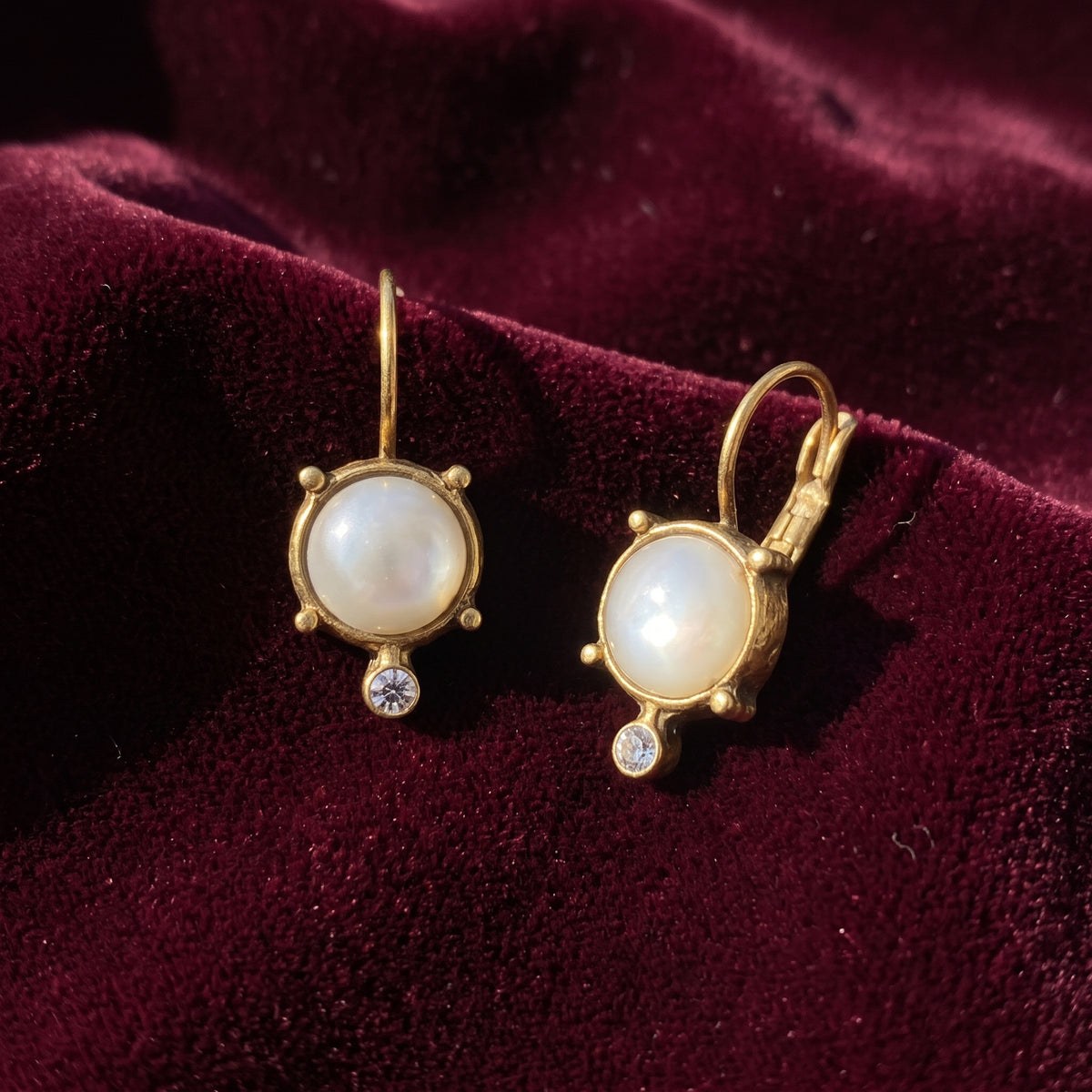 Antiquities Couture Faux Pearl and Crystal Leverback Drop Earrings displayed on a deep burgundy velvet fabric background.