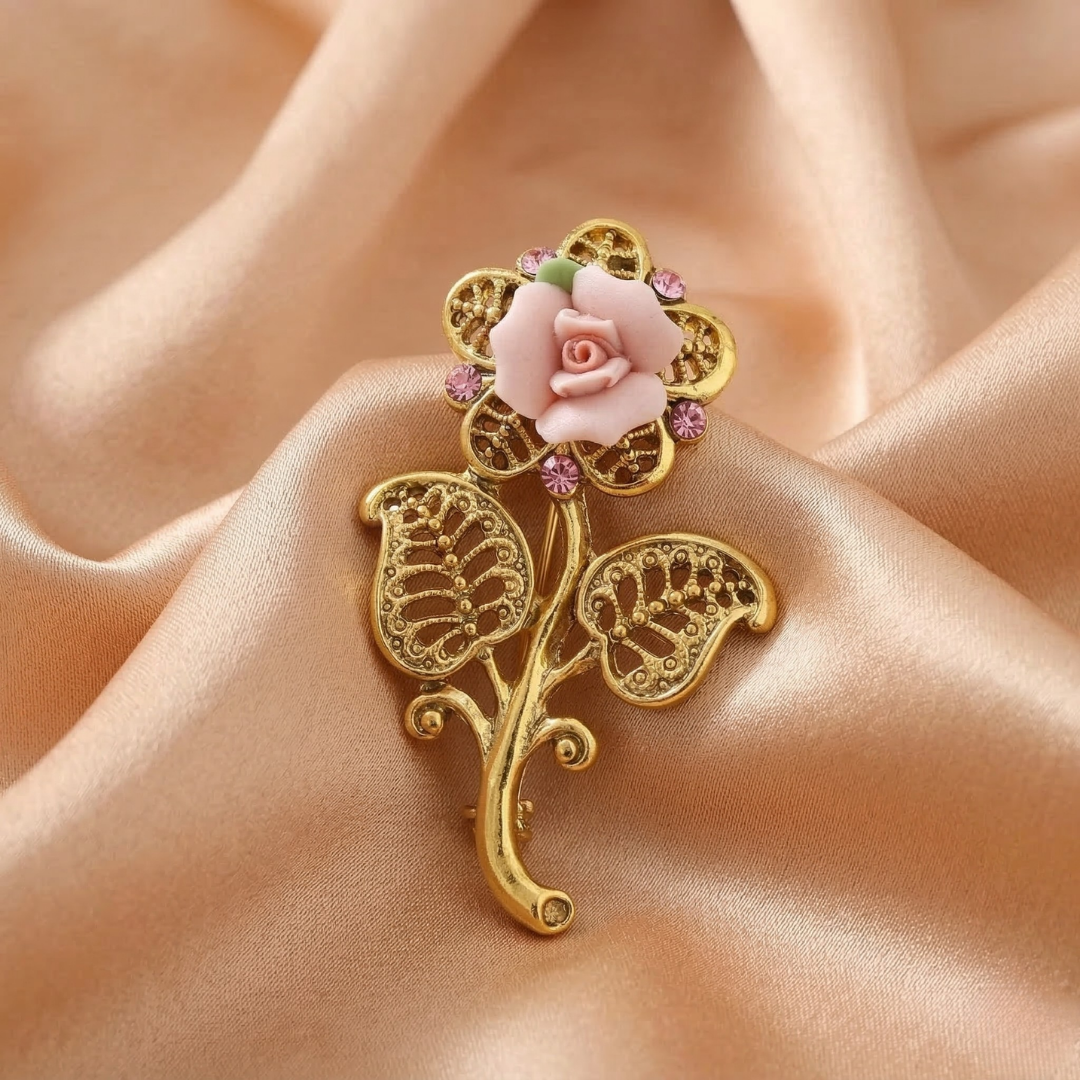 Gold brooch with pink porcelain rose and pink glass crystals on a beige fabric background