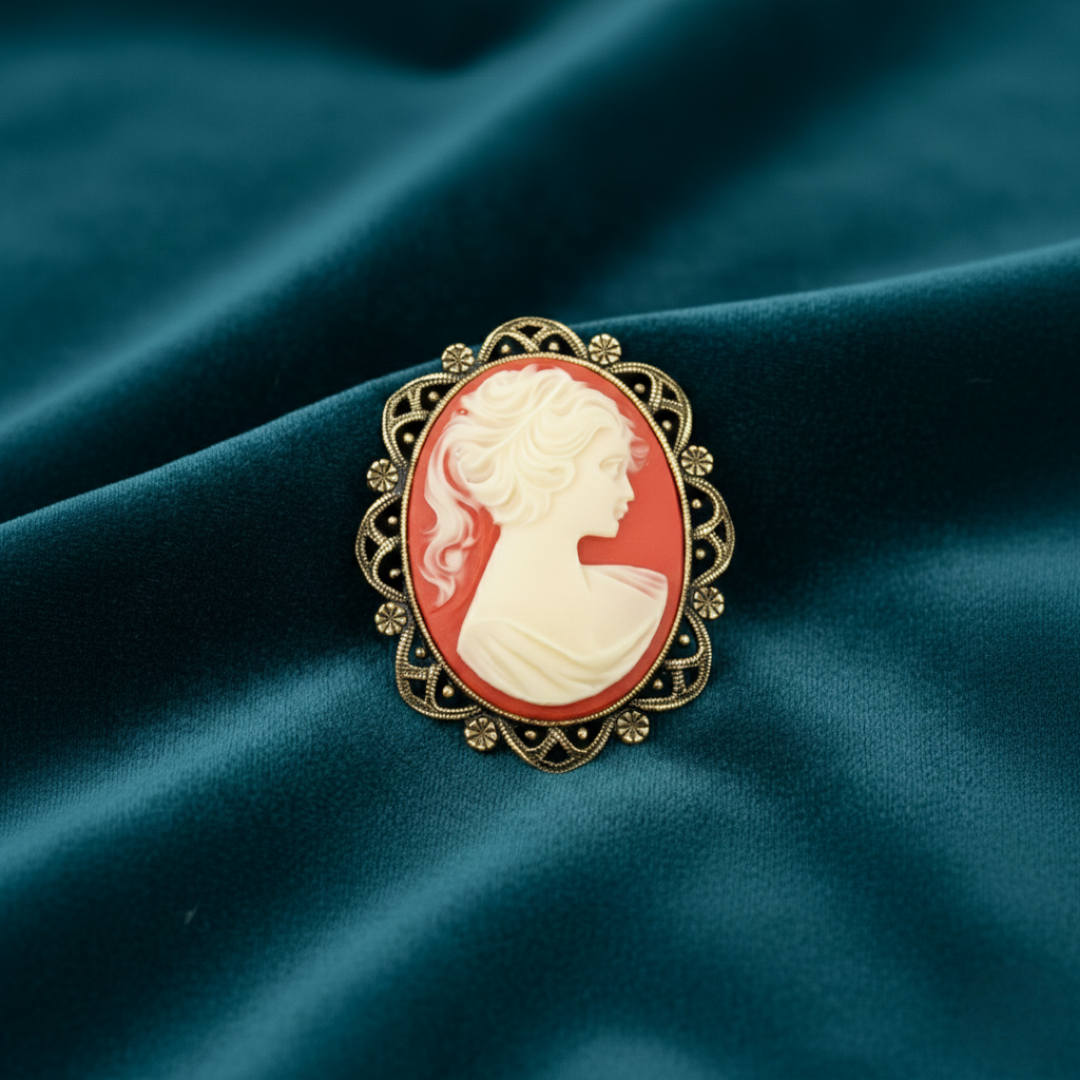 Cameo brooch with gold frame on a dark blue fabric background
