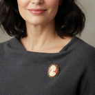 Woman wearing a dark gray sweater with a brooch on a neutral background
