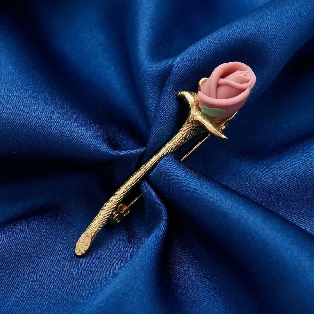 Rose-shaped brooch made from porcelain and 14K gold-dipped metal on a blue fabric background