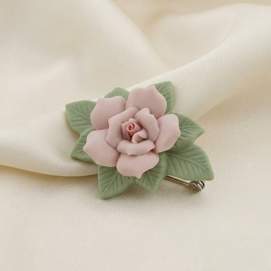 Pink rose-shaped hair clip with green leaves on a beige fabric background