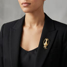 Woman in a black blazer wearing a gold tone cat brooch with clear crystal accents