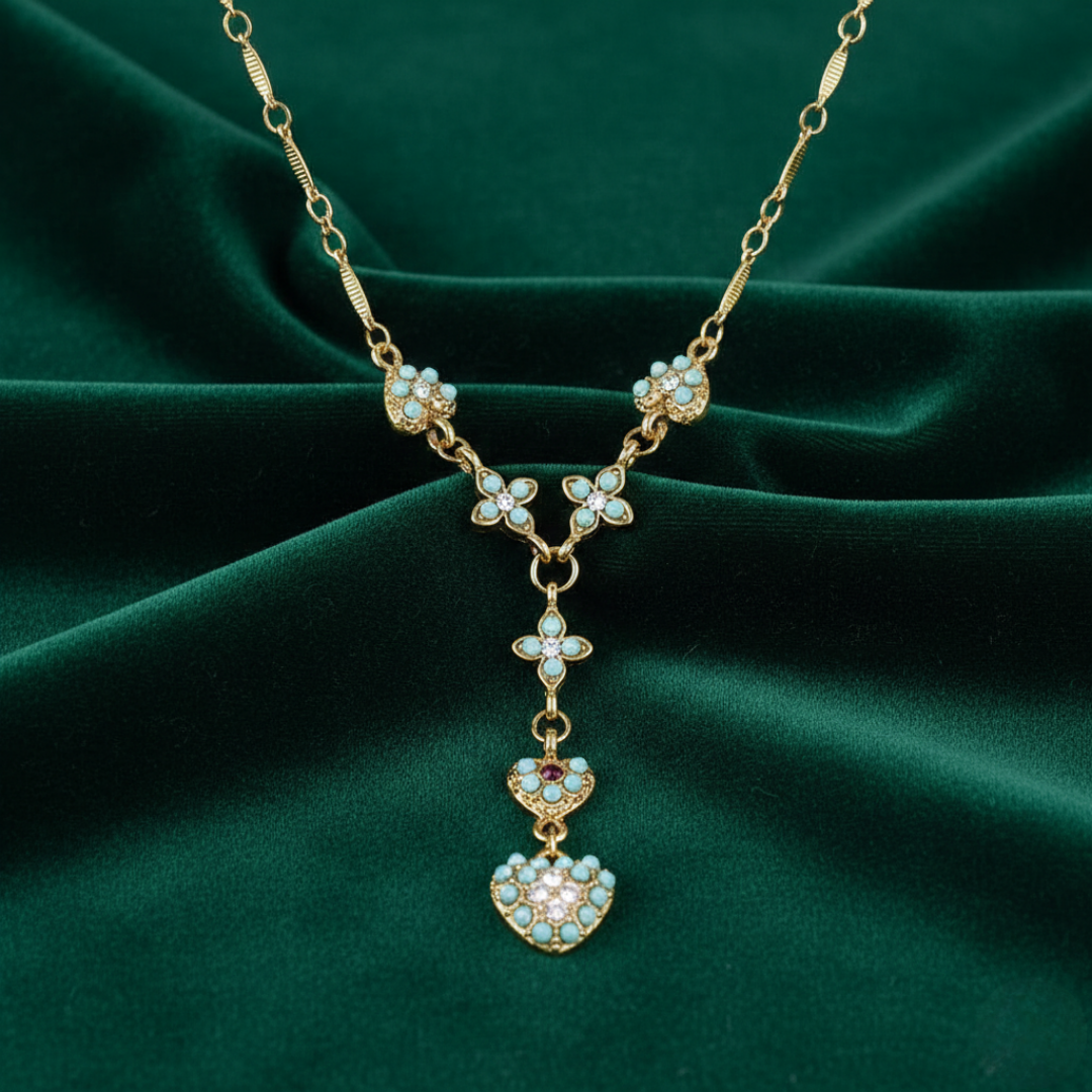 Gold necklace with heart-shaped pendants on a green fabric background