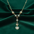 Gold necklace with heart-shaped pendants on a green fabric background
