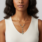 Woman wearing a gold necklace with turquoise stones against a neutral background