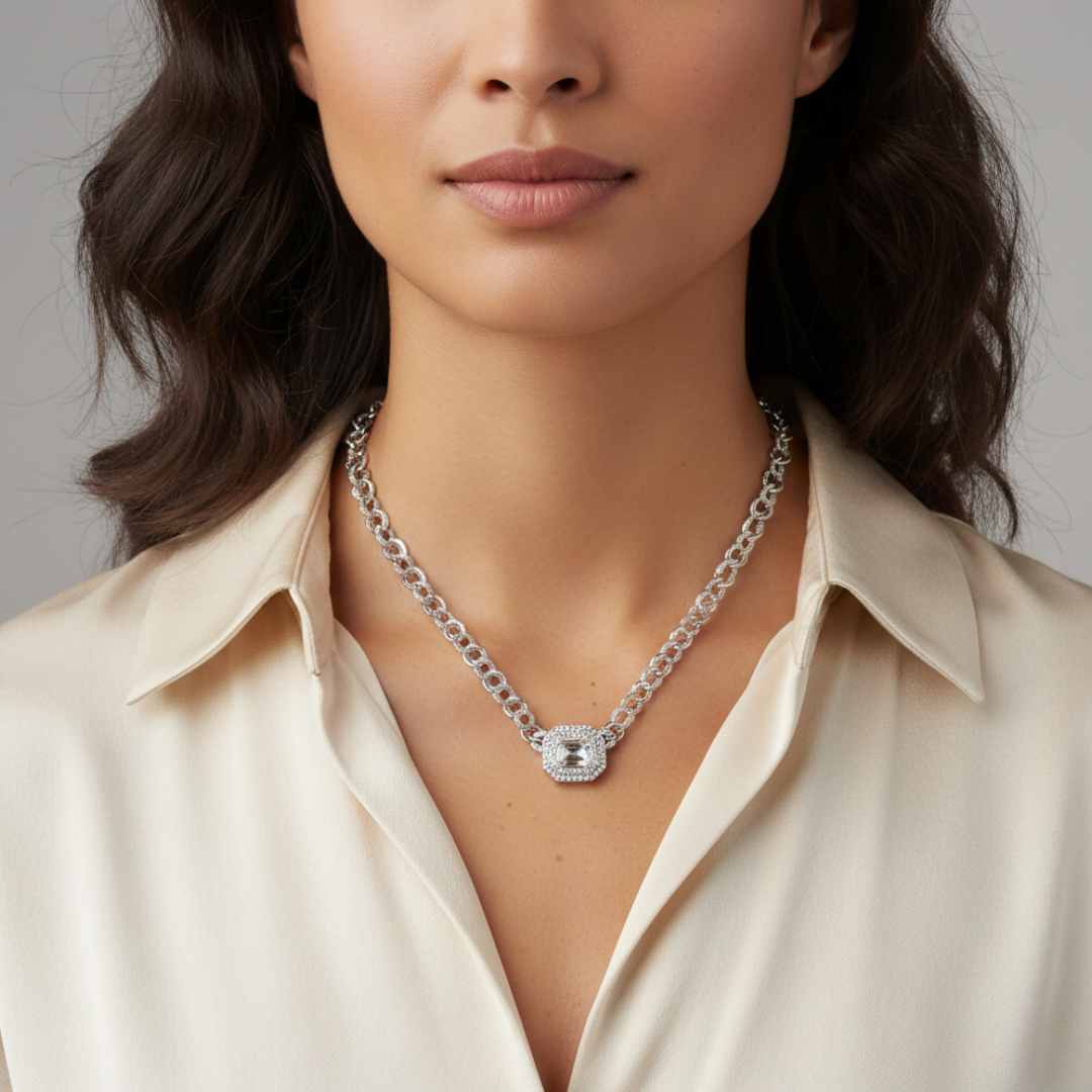 Woman wearing a silver chain necklace with a clear crystal pendant against a neutral background
