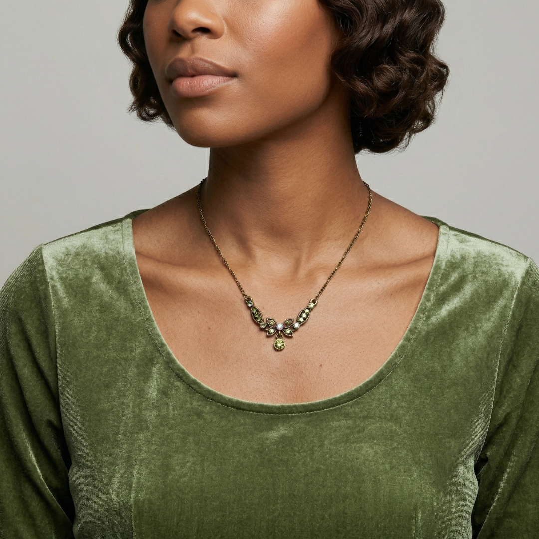 Woman wearing a green velvet top and necklace against a gray background