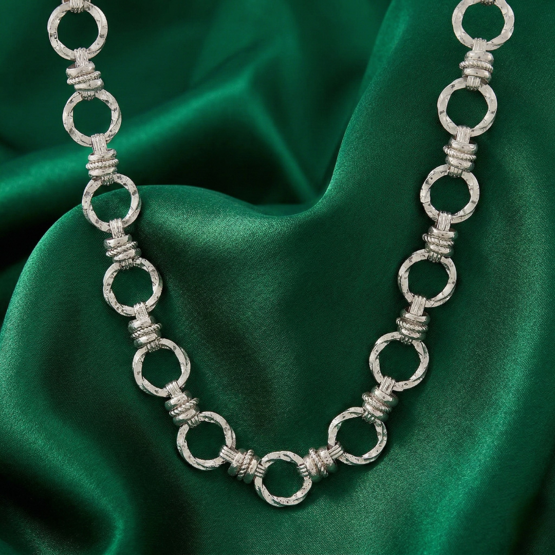 Silver tone necklace on a green fabric background
