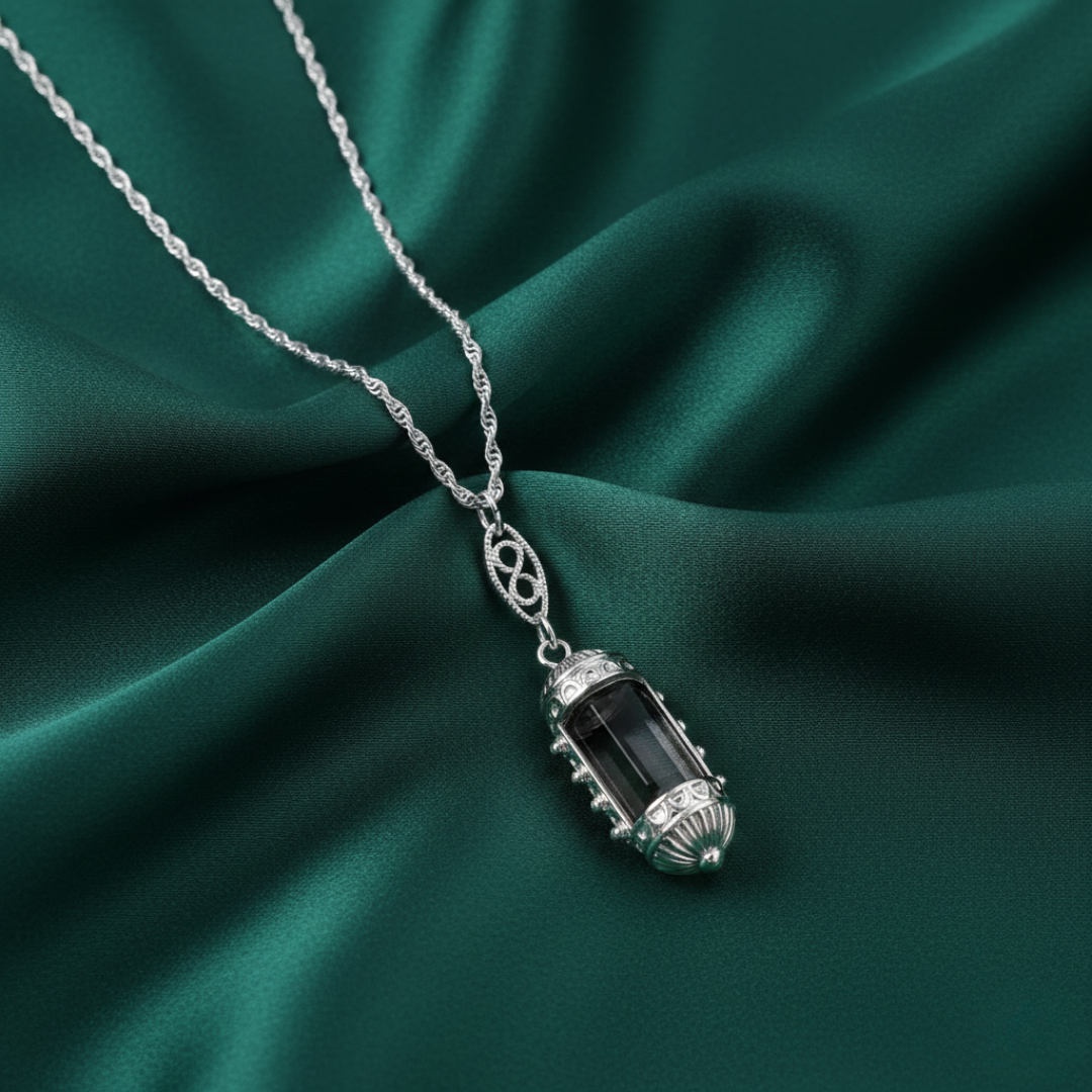 Silver necklace with a pendant on a green fabric background