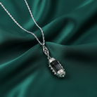 Silver necklace with a pendant on a green fabric background