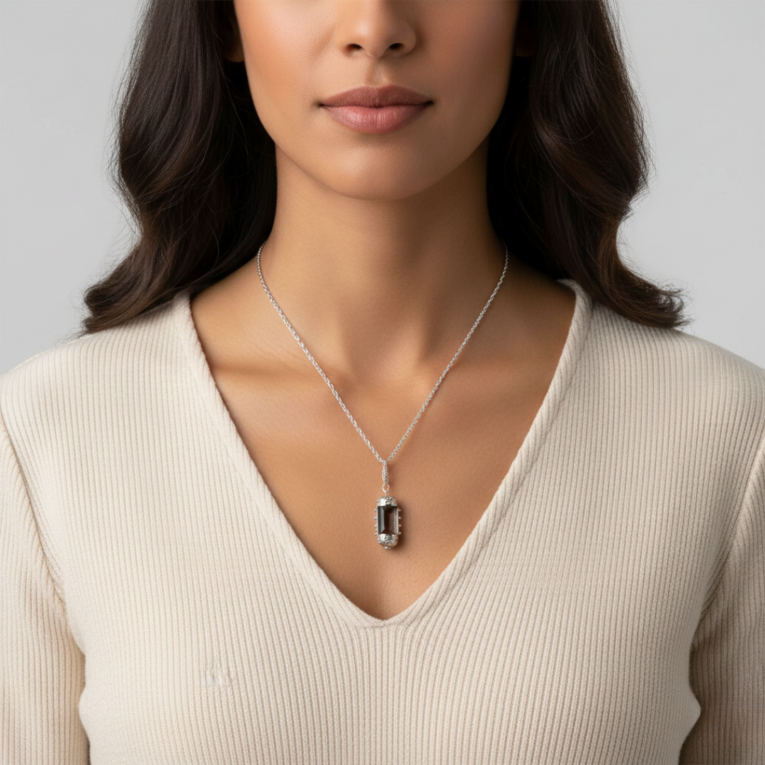 Woman wearing a silver necklace with a pendant against a neutral background