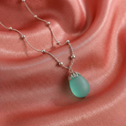 Necklace with an aquamarine frosted glass pendant on a pink fabric background