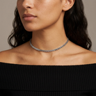 Close-up of a woman wearing a silver necklace against a neutral background