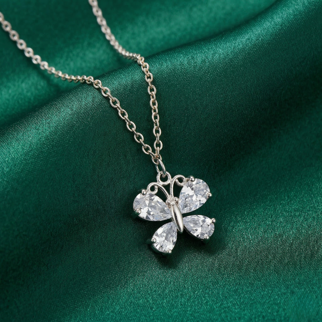 Butterfly-shaped pendant necklace on a green fabric background