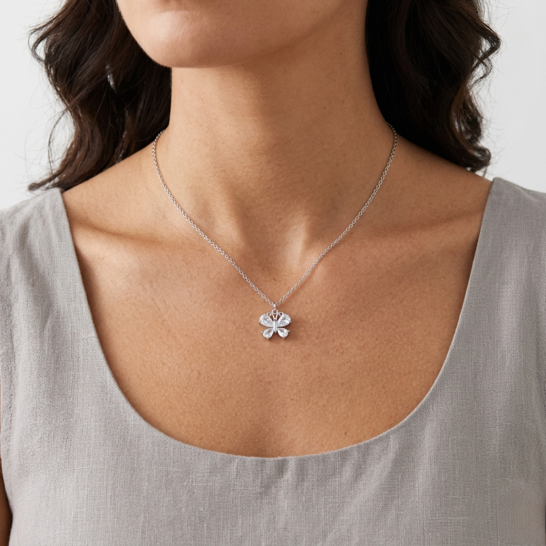 Silver necklace with a crystal butterfly pendant worn by a person against a neutral background