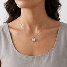 Silver necklace with a crystal butterfly pendant worn by a person against a neutral background