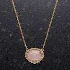 Pink Moonstone Crystal Accent Pendant Necklace resting on dark stone surface