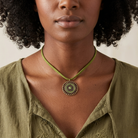 Woman wearing a green necklace with a pendant against a neutral background