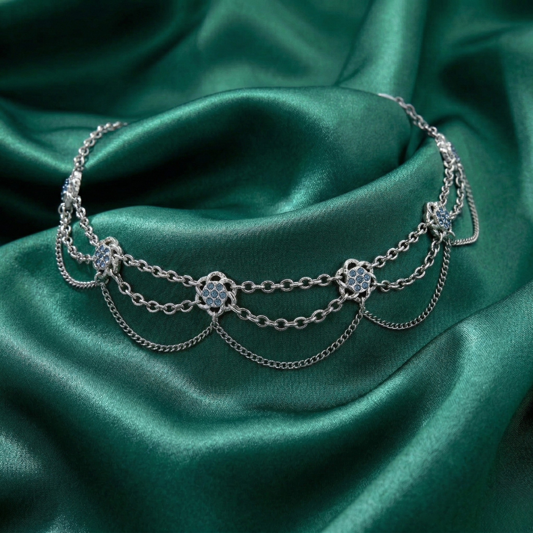 Silver chain choker bracelet with blue gemstones on green satin fabric