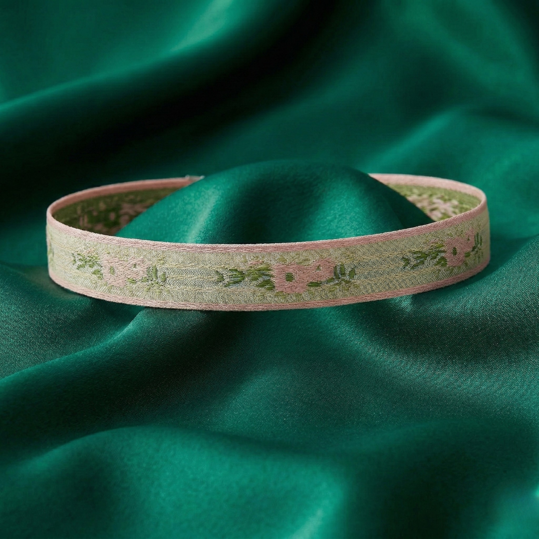 Pink choker necklace with floral patterns on a green satin background
